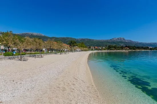 Oblázková pláž s pozvolným vstupem do moře v městě Kaštel Stari.