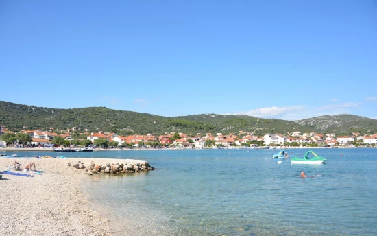 Oblázková pláž s pozvolným vstupem do moře v městečku Vinišće.