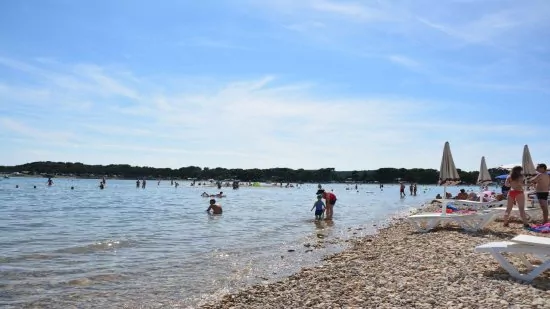 Oblázkovo písčitá pláž v centru města Medulin.