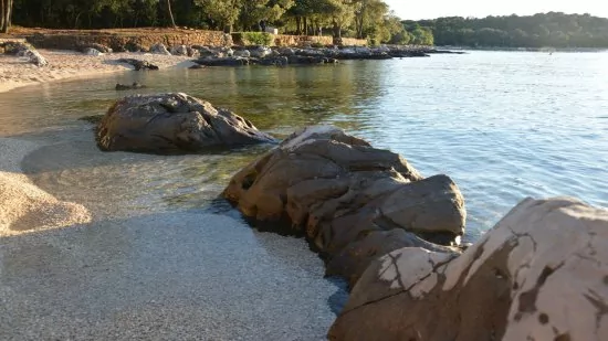 Oblázková pláž ve městě Rovinj (Lone Bay).