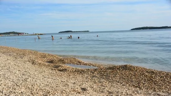 Fažana oblázková pláž s pozvolným vstupem do moře.
