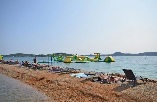 Vodice oblázková pláž s pozvolným vstupem do moře.